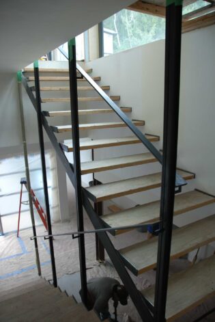 Brandner Design "Hilltop Modern" Stairs made with minimal steel supports, Black stained White Oak treads with open risers and large glass panels.