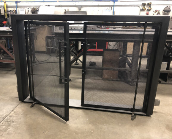 Ascent Fireplace Doors on blackened steel doors with mesh screen on pivot hinges.