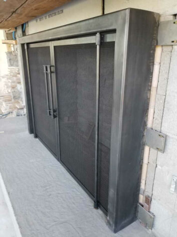 Ascent Fireplace Doors on blackened steel doors with mesh screen on pivot hinges.