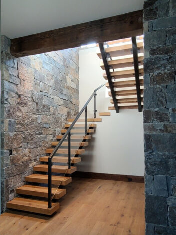 Ascent Staircase with oak treads and glass panels fasten to a blackened steel stair.