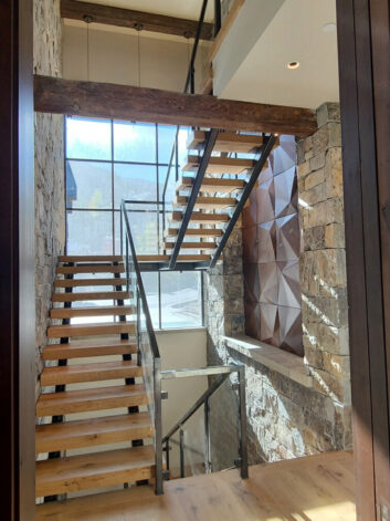 Ascent Staircase with oak treads and glass panels fasten to a blackened steel stair.