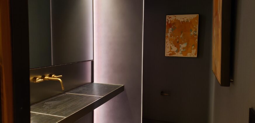 Powder Grate Sink and Vanity made of a sleek stainless steel and brass faucet and sconce for a touch of warmth.