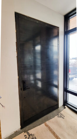 Custom front door with Blackened Stainless Steel Glued Panels by Brandner Design