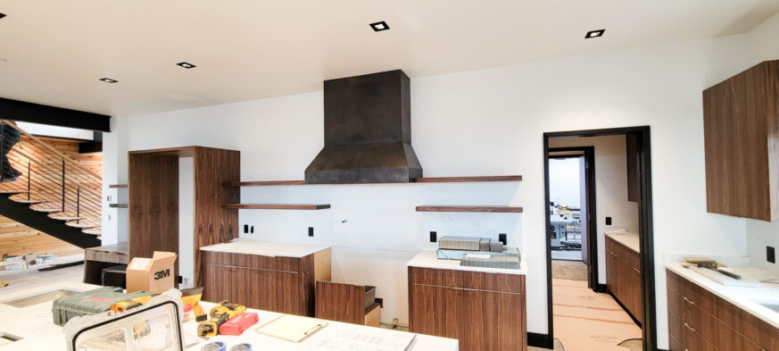 Kitchen Cabinets with walnut veneers and sedan pulls and Kitchen hood made of natural etched steel by Brandner Design