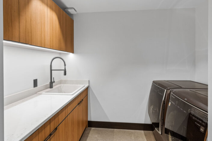 Sales Place Residence laundry room with grain-matched veneer cabinets and black sedan pulls