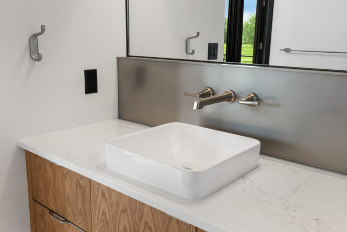 Sales Place Residence bathroom with stainless steel backsplash and waknut veneer cabinets with sedan pulls