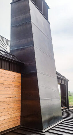 The Sales Place Weathered Black Dark Stainless Steel Chimney Cap with Overlap Steel Siding.